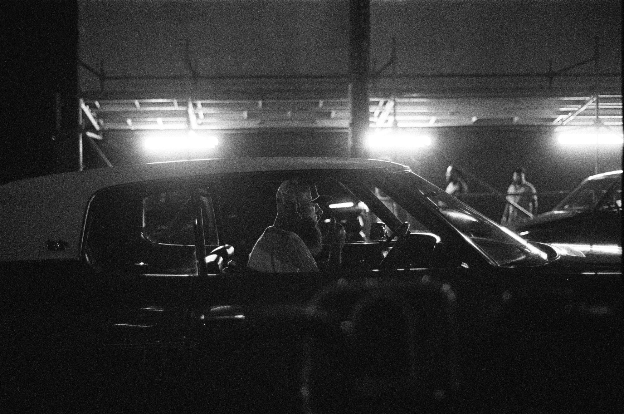 A driver in a car under bright overhead lights