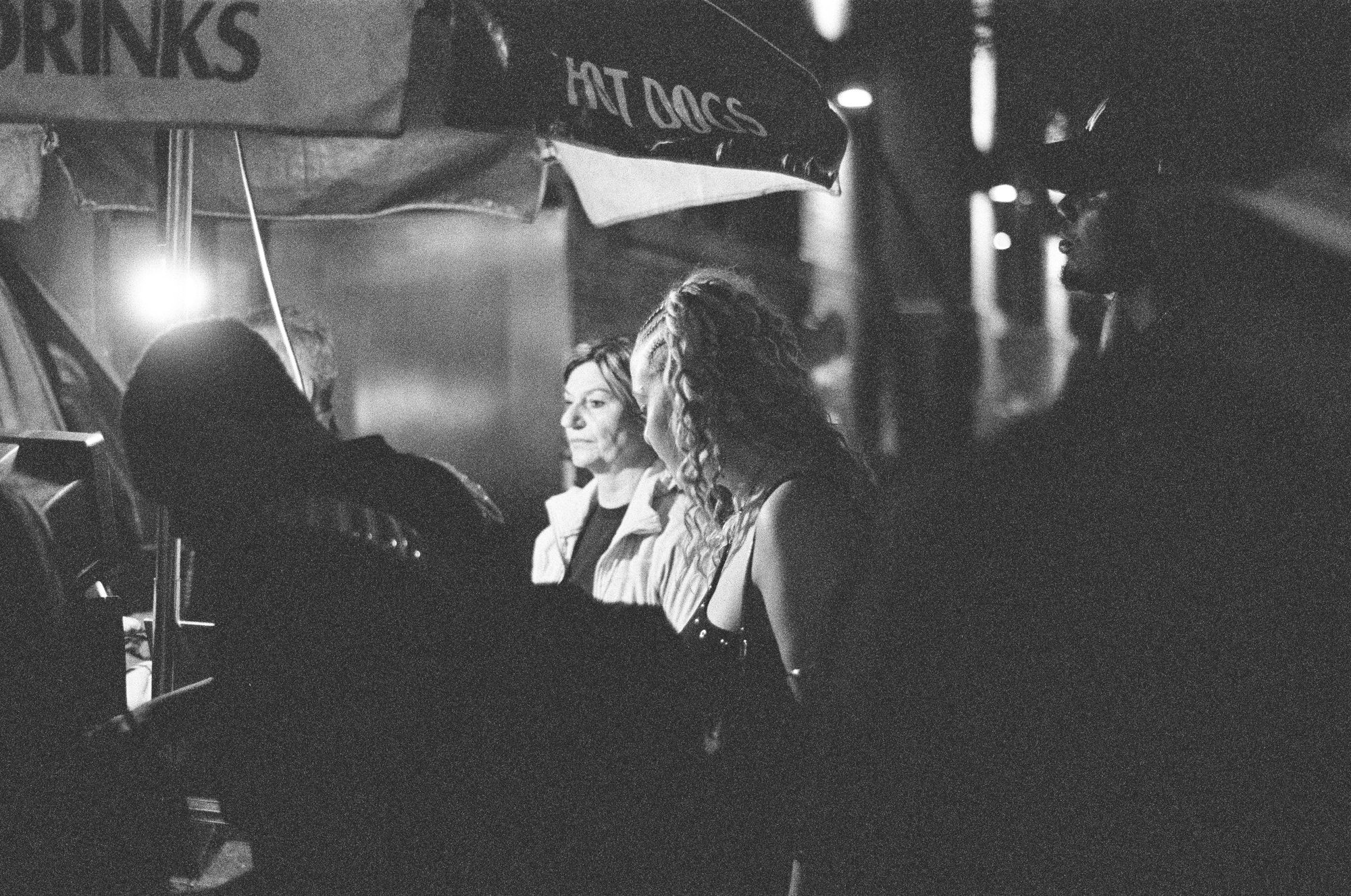 Women laughing under a hot-dog cart umbrella