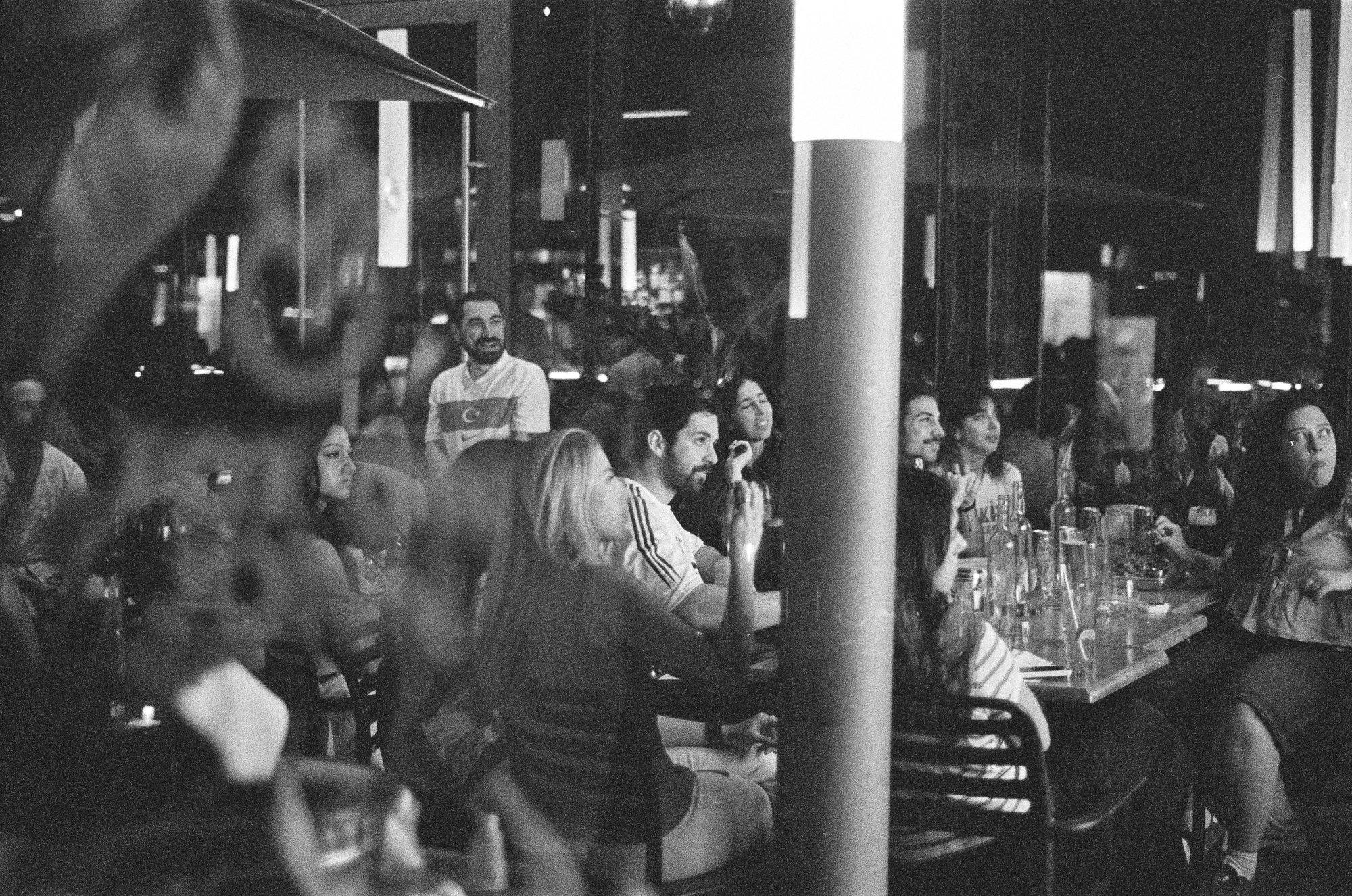 Diners packed around patio tables behind a pole