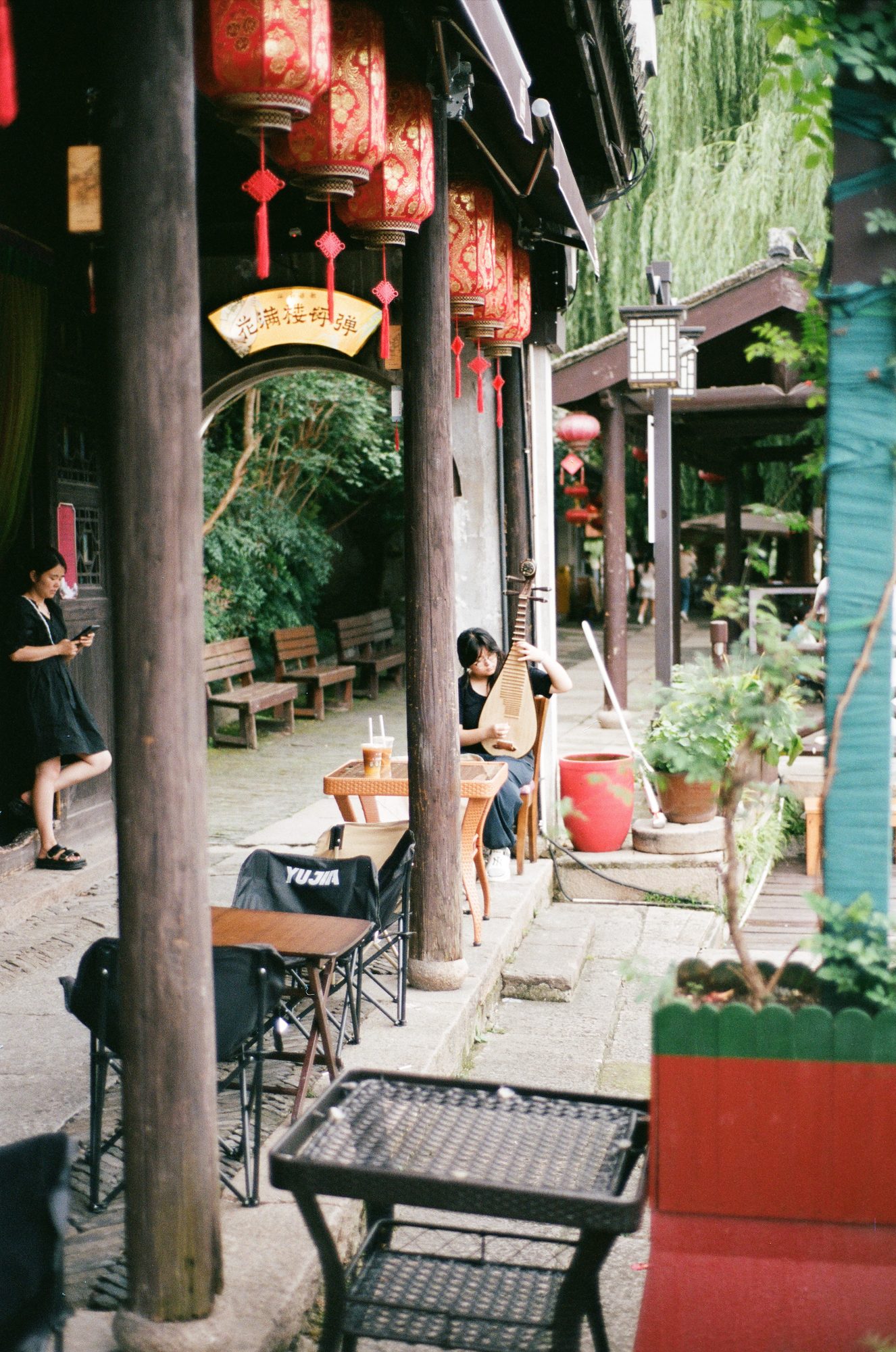 Red lanterns and wooden pillars along a canal-side walk