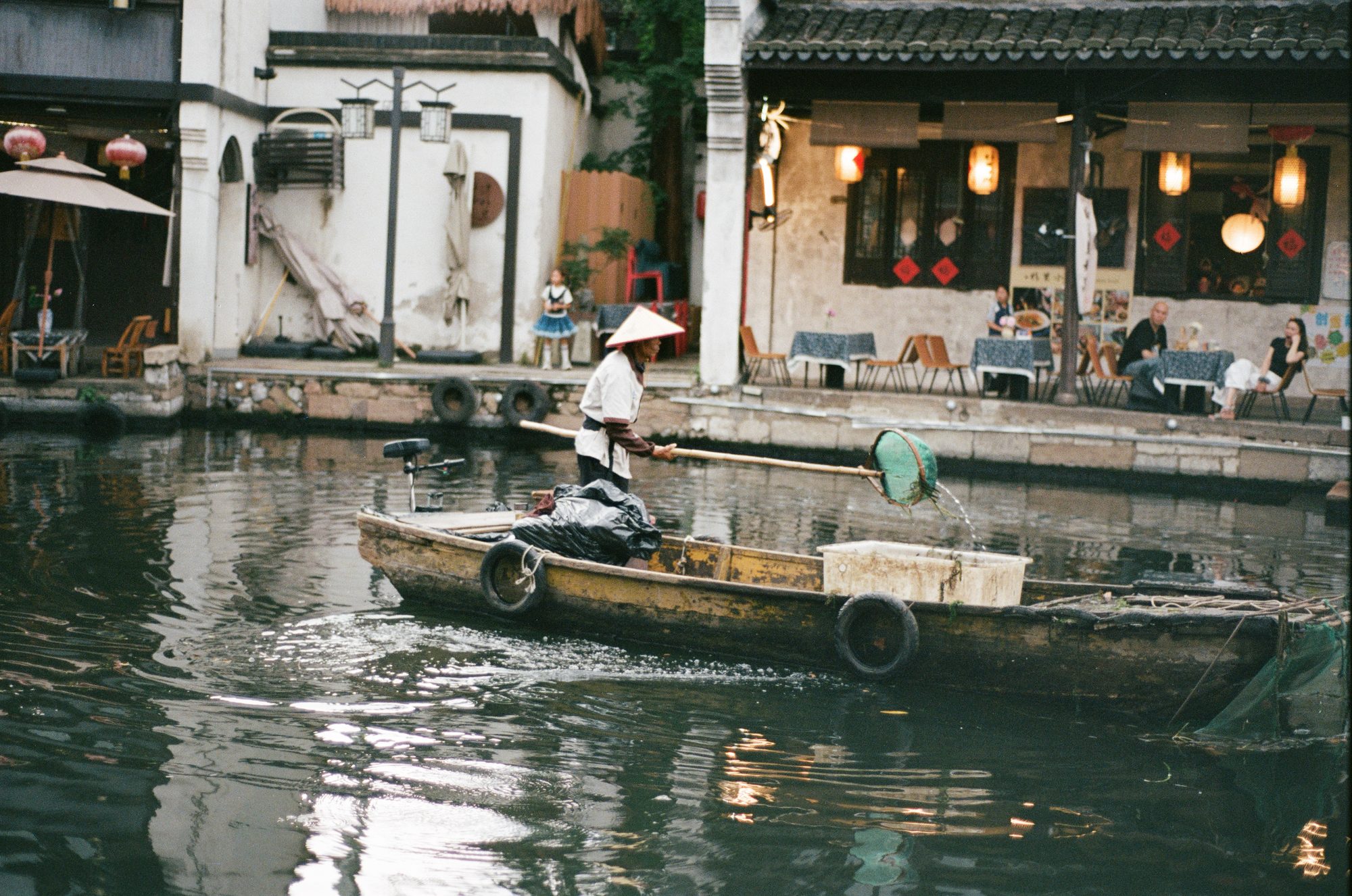 A boatman paddling past a canal-side café
