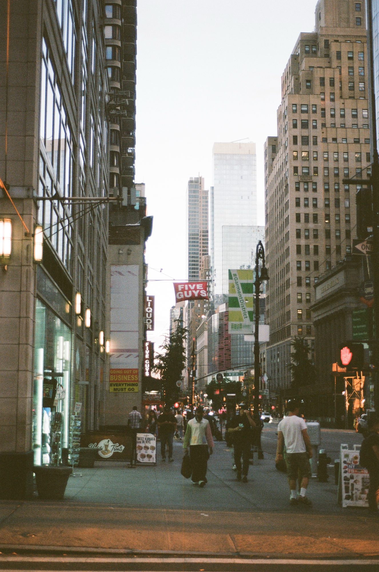 Tall buildings closing in on a narrow street in late light