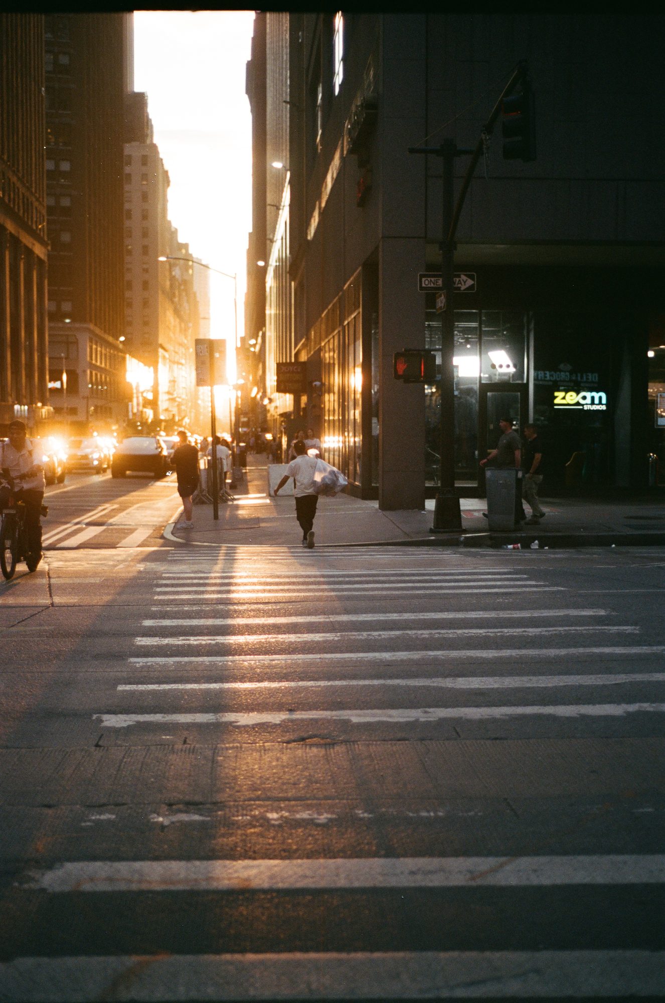 The sun sitting at the end of a narrow Manhattan street, the crosswalk in shadow