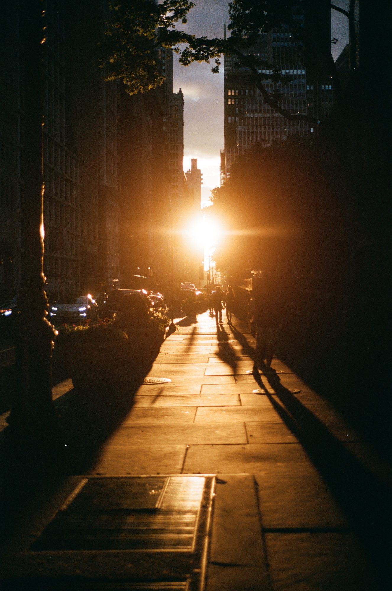 The sun setting at the end of a Midtown street, pedestrians silhouetted on the glowing pavement