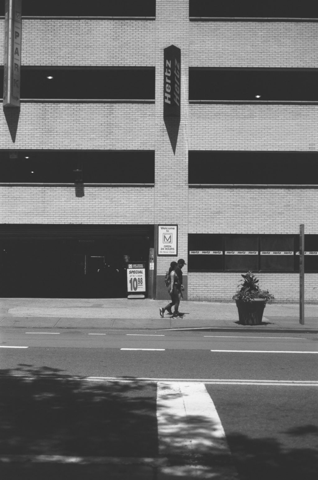 A brick facade over an empty crosswalk and a lone pedestrian