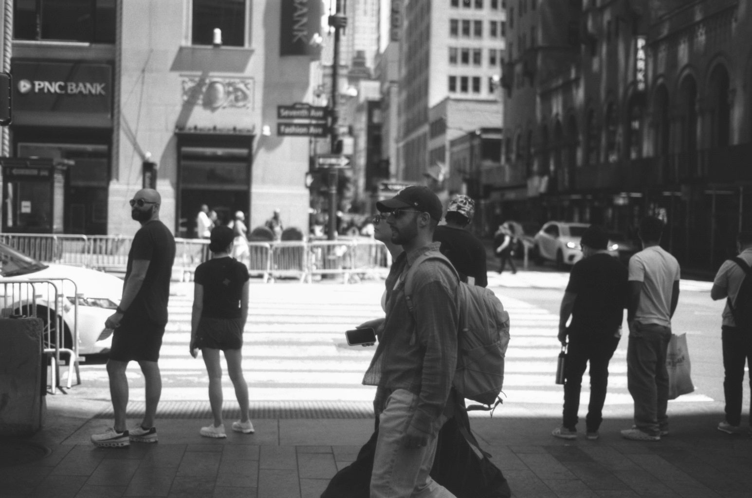 Pedestrians crossing in hard sunlight between office towers