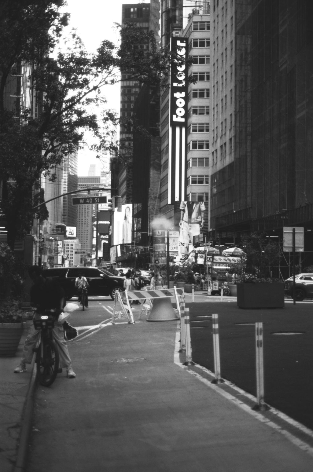 A cyclist down a narrow street under a Foot Locker sign