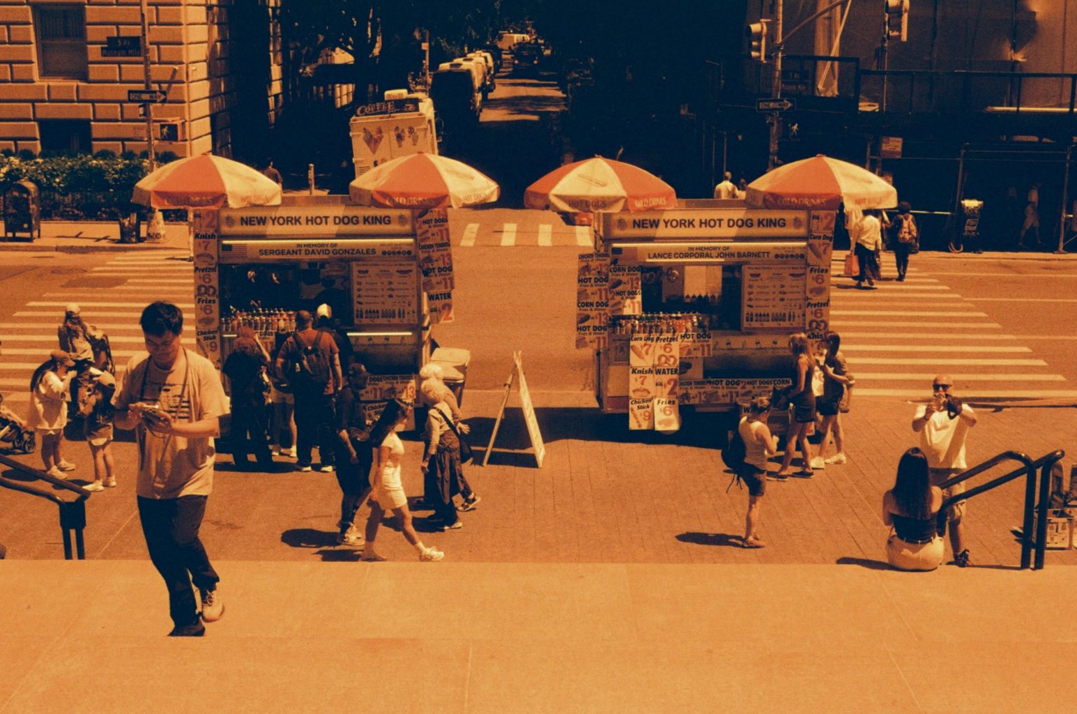 Vendor umbrellas and pedestrians on a sunny plaza