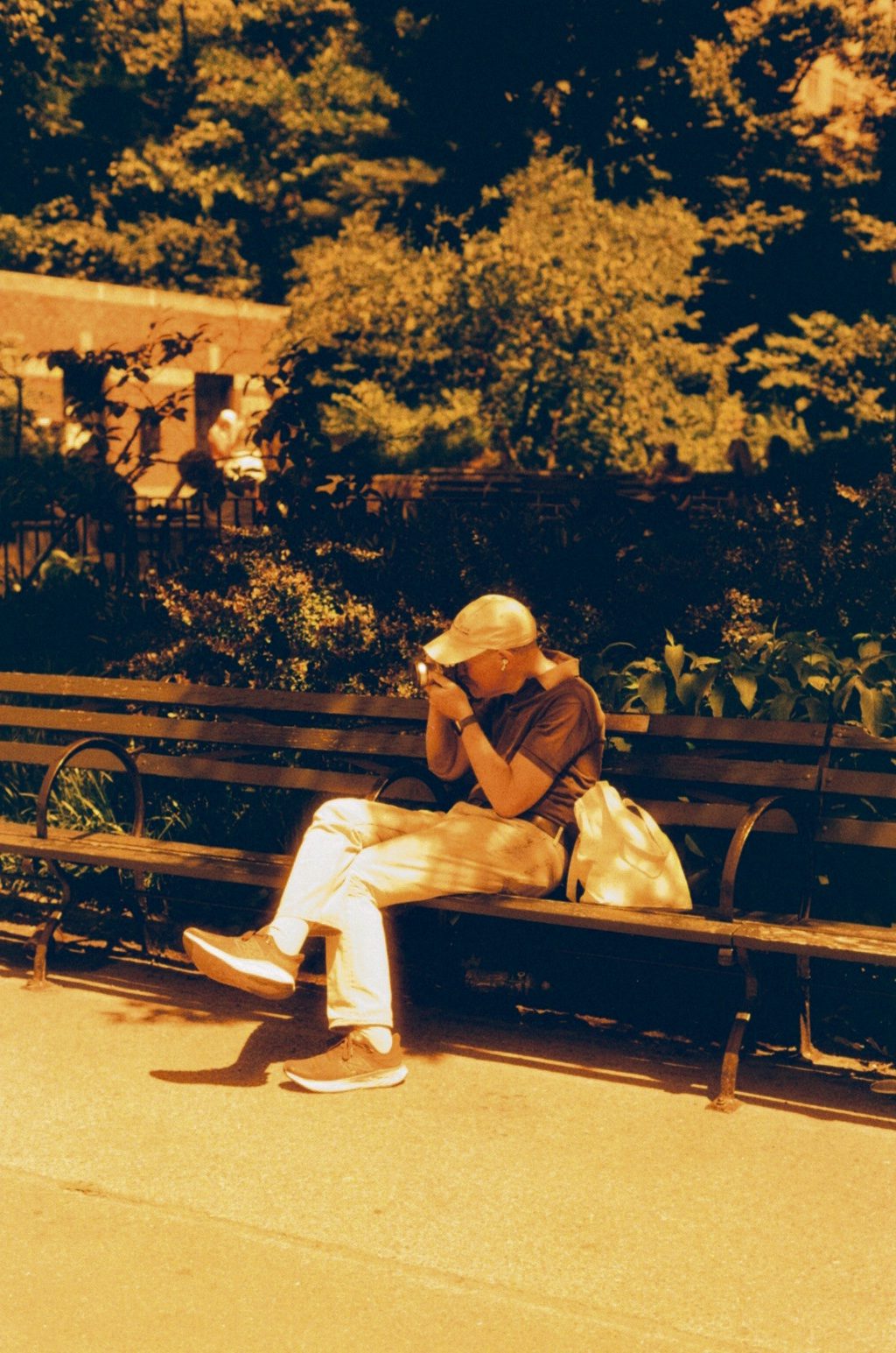 A man resting on a park bench in amber light