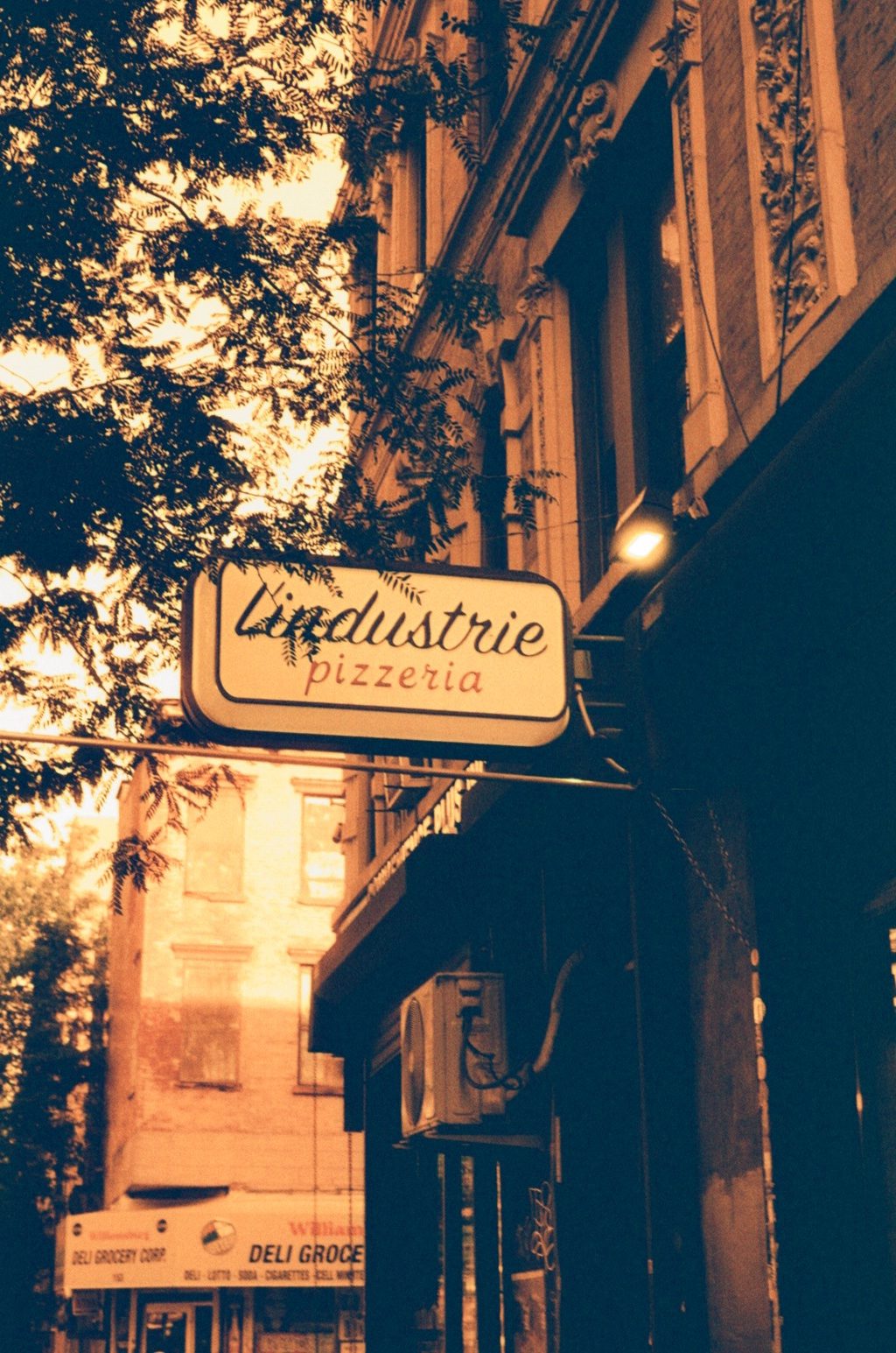 A pizzeria sign hanging over a brownstone street