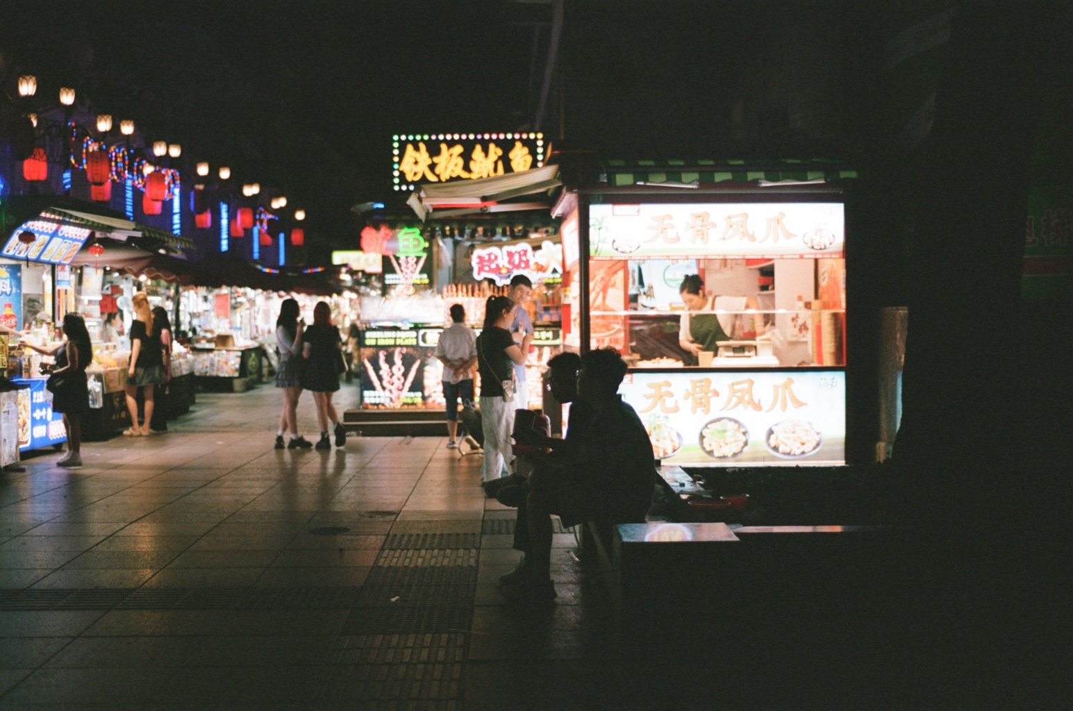 Lit food stalls along a dark pedestrian street