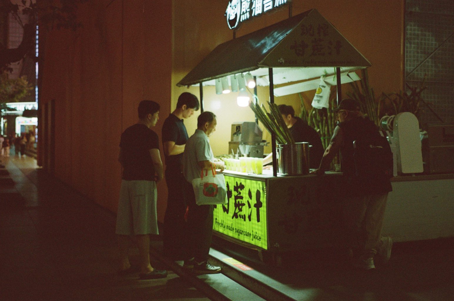 People queuing at a green-lit drinks kiosk