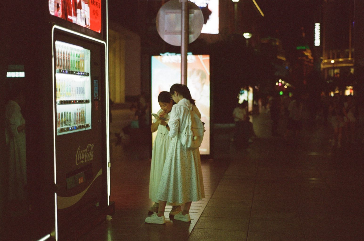 Two women beside a glowing vending machine