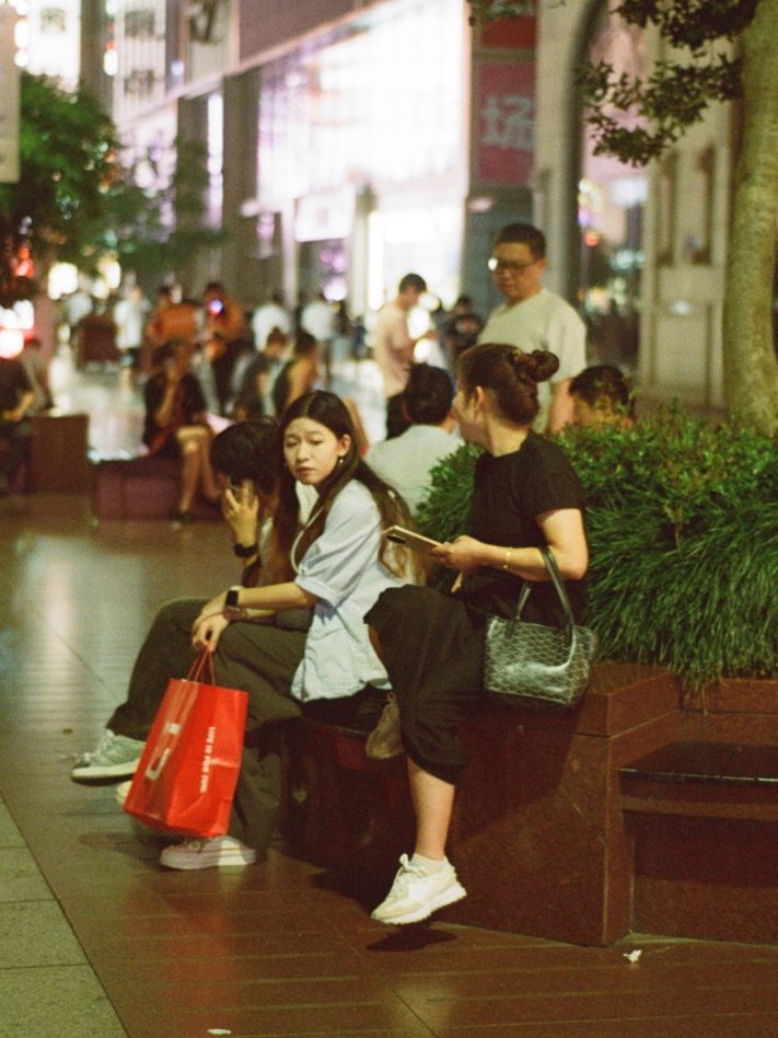 Young women resting on a planter edge, a red shopping bag at their feet