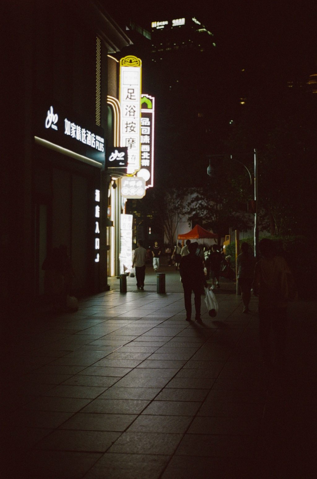 A dark street under a vertical neon sign