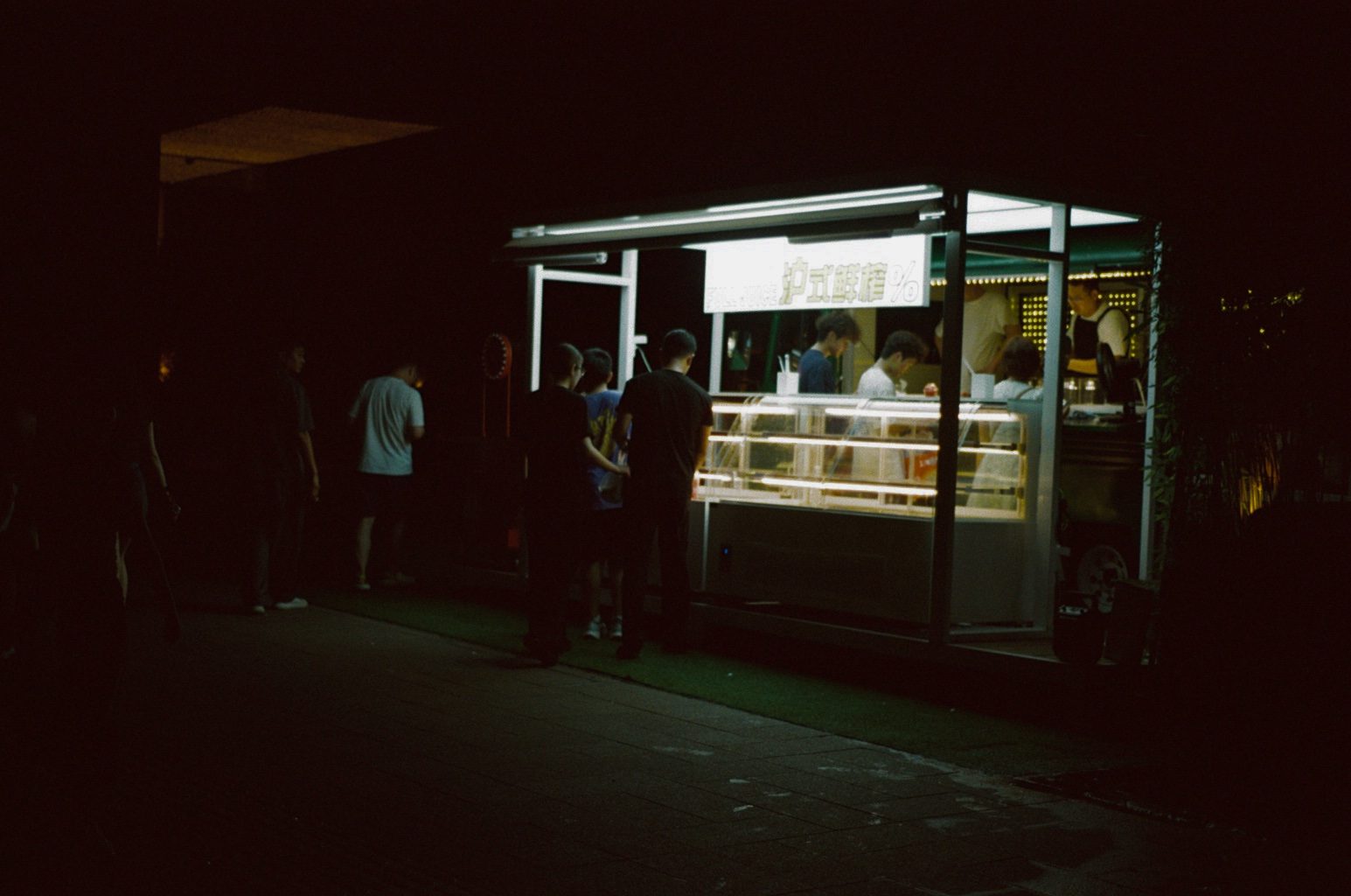 A small lit kiosk in a dark plaza
