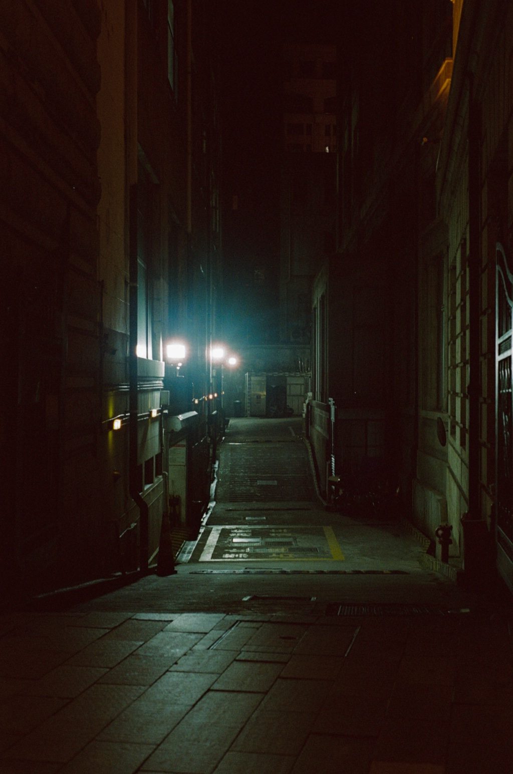 A dark back alley lit by a single lamp